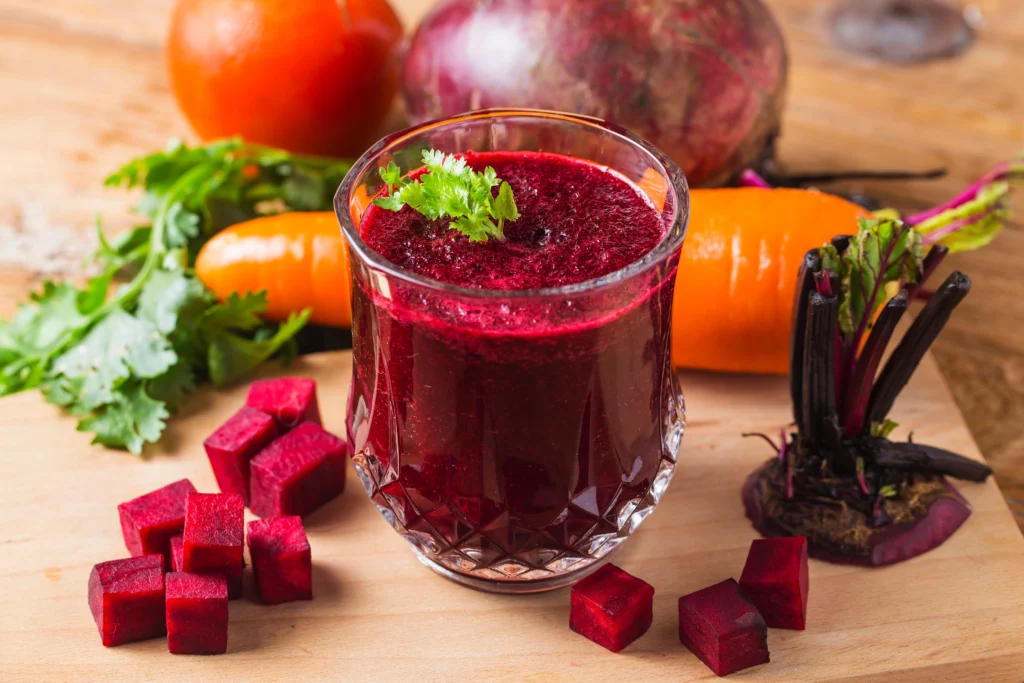 A glass of carrot and beetroot juice with fresh carrot and beetroot slices